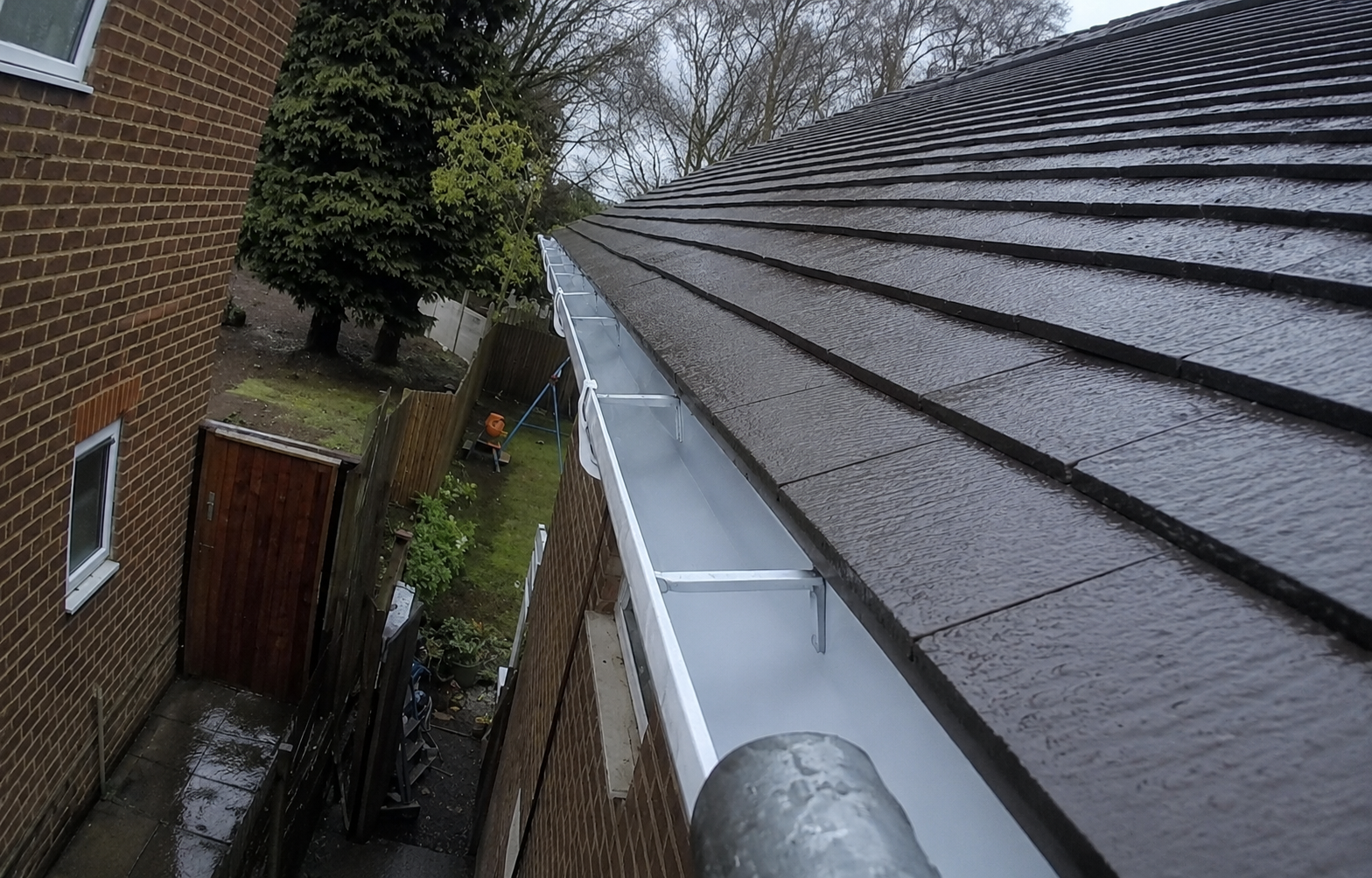 Cleaned gutter system with unobstructed rainwater drainage and fully tested brackets and downpipes