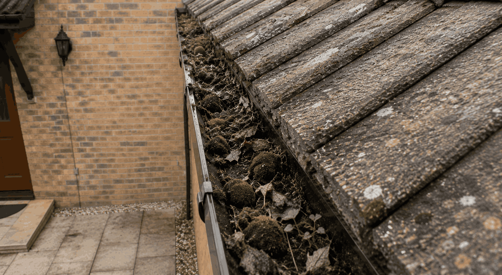 External brick wall showing vertical water staining from overflowing eaves gutters